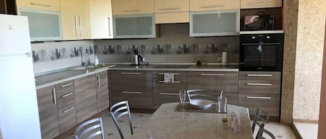 Apartamento Confort | Cocina privada | Frigorífico grande, microondas, horno y placa de cocina