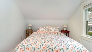 A bedroom with a bed, two nightstands, and a window.