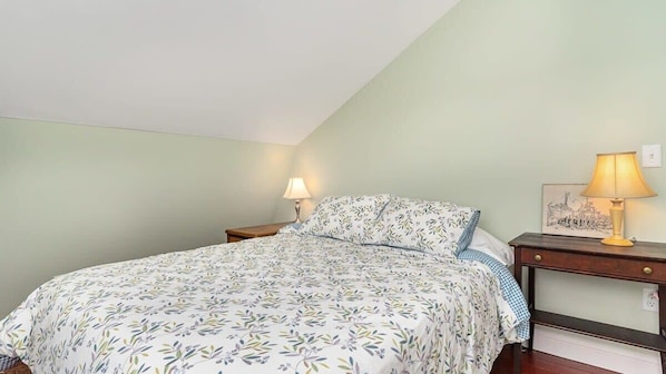 Ein Schlafzimmer mit einem Bett, zwei Nachttischen und einem Beistelltisch.