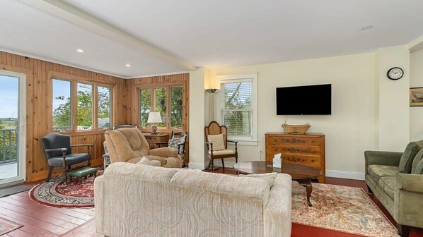 A cozy living room with a sofa, armchairs, a television, and a wooden cabinet.