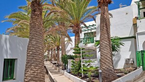 A row of white buildings with green accents, palm trees, and a clear blue sky. - Apartment PALM GARDEN - Costa Calma - Fiber Optic Internet - Pool (Costa Calma)