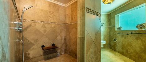 A bathroom with a shower, toilet, and a bench.