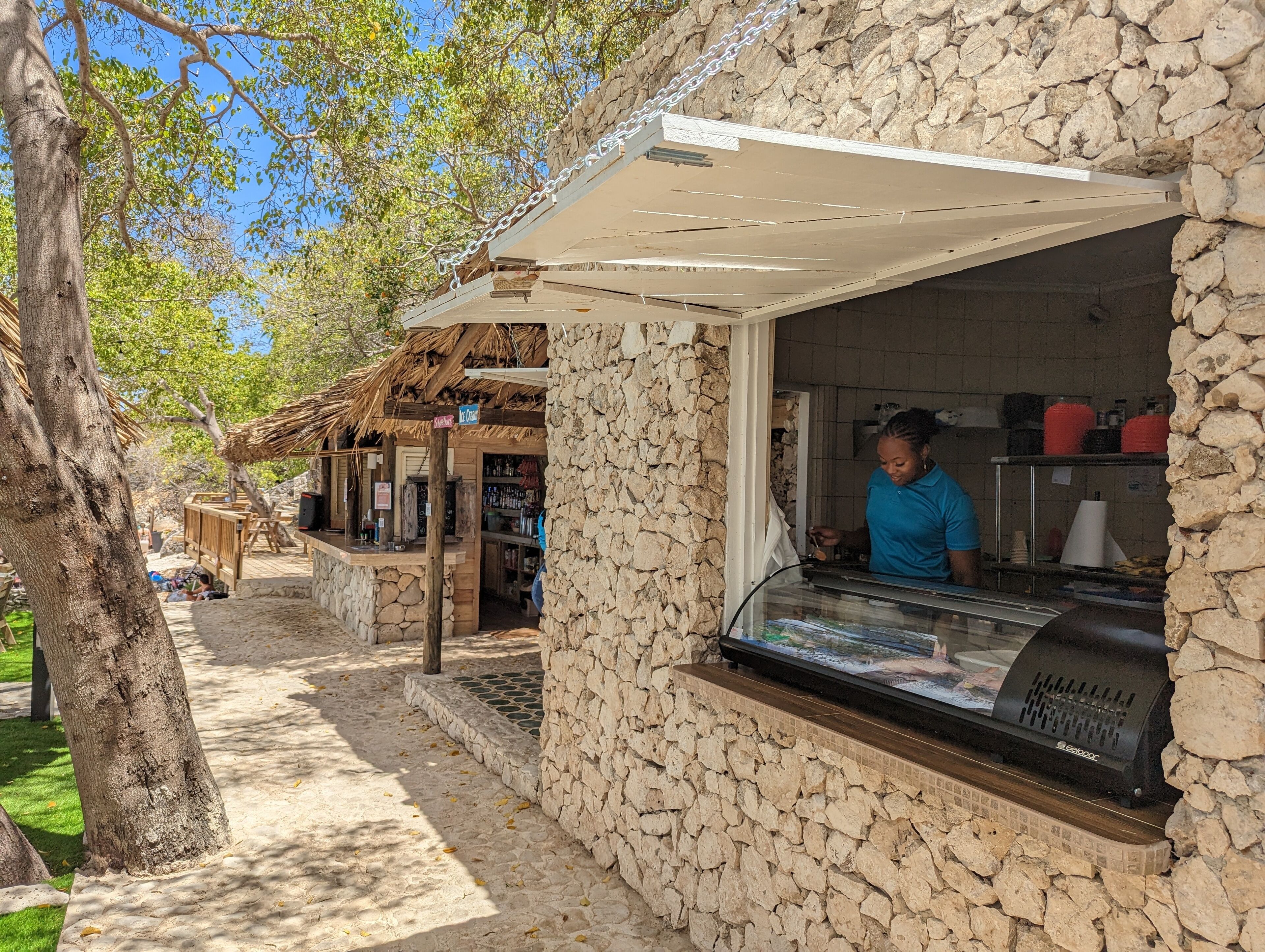 A rustic outdoor café with stone walls and a wooden counter.