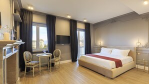 Ein Hotelzimmer mit einem großen Bett, einer Sitzecke mit Tisch und Stühlen, einem Kamin und einem Fernseher.