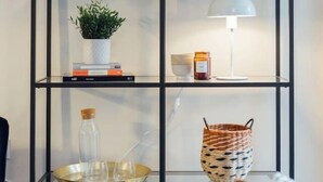 Ein schwarzes Metallregal mit verschiedenen Dekorationen und einer hängenden Pflanze.
