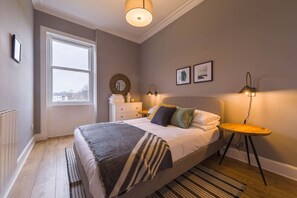 Een slaapkamer met een bed, nachtkastjes, een raam en uitzicht.