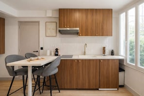Una cocina moderna con armarios de madera, encimera blanca y ventana que deja entrar luz natural.