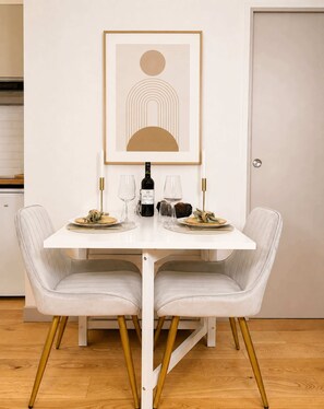 A dining table with two chairs, a bottle of wine, and empty wine glasses.