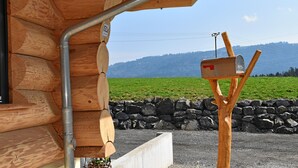 Una cabaña de madera con buzón y un muro de piedra.