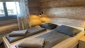 Una habitación tipo cabaña de madera con cama, almohadas y mesita de noche.
