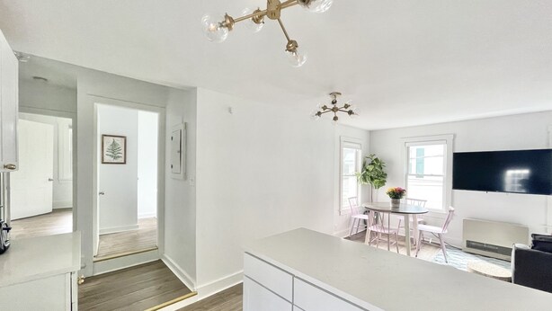 Een moderne keuken met witte kasten, een centraal eiland en een eethoek met een tafel en stoelen.