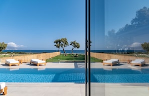 A poolside area with lounge chairs and a view of the sea.