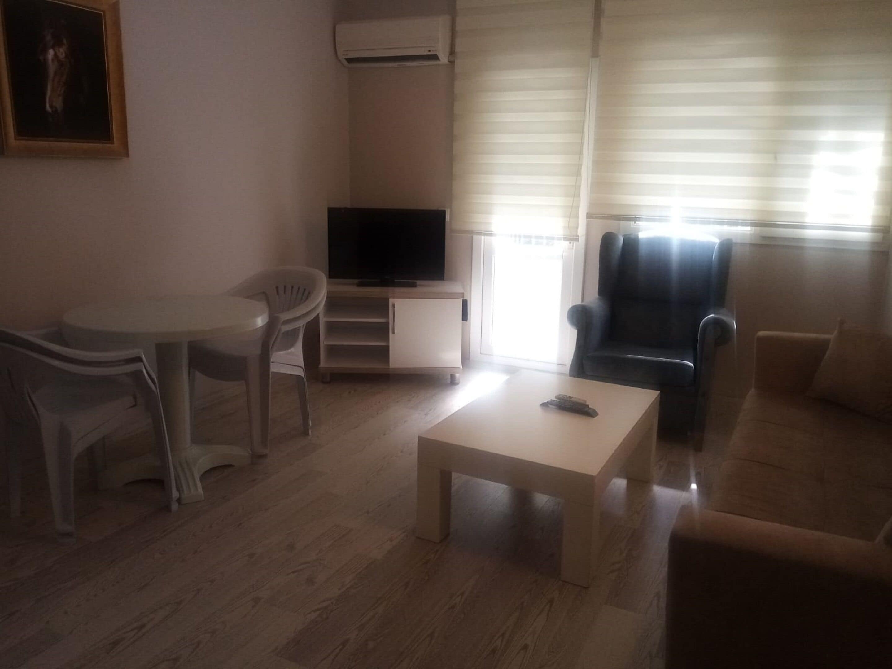Een woonkamer met een bank, een televisie op een dressoir, een kleine tafel en een stoel.