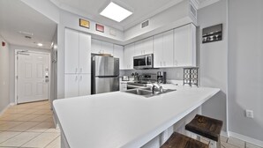 Una cucina moderna con mobili bianchi, elettrodomestici in acciaio inossidabile e una grande isola con lavello.