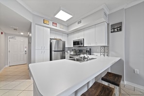 Una cocina moderna con armarios blancos, electrodomésticos de acero inoxidable y una isla grande con un fregadero.