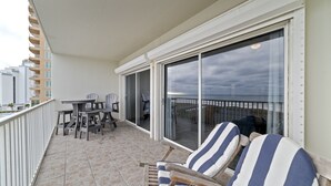 Un balcone con tavolo e sedie, una poltrona da relax a righe e vista sulla città.