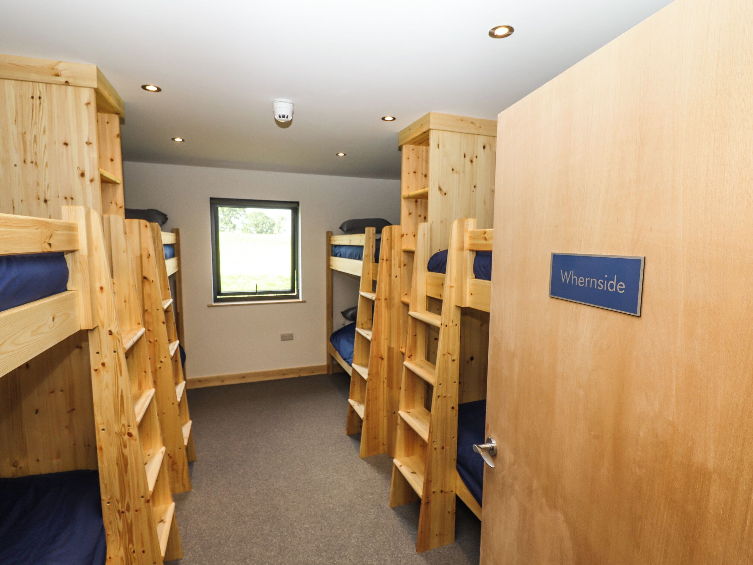 A room with bunk beds, a window, and a sign reading "Whernside".