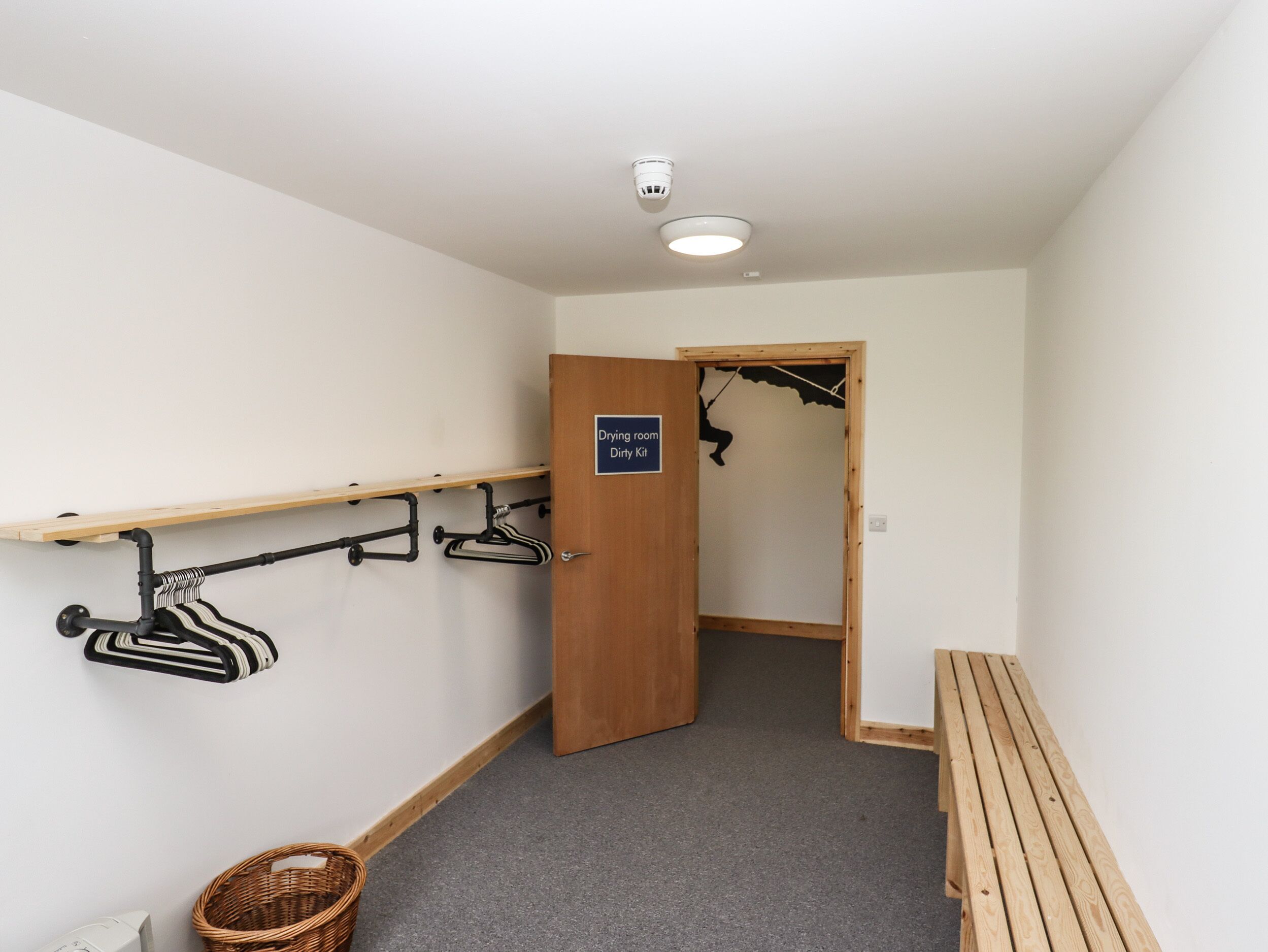 A hallway with a drying room sign, a bench, and a basket.