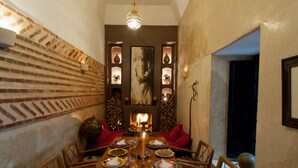 A dining room with a brick wall, a fireplace, and red chairs. - Riad Magellan with swimming pool & Jaccuzzi 2 steps from Jamaa el Fna square (Marrakech)