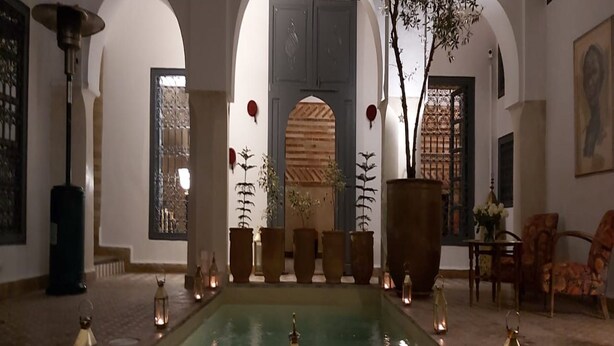 A pool area with a fountain, surrounded by arches and potted plants, with lanterns along the pool's edge. - Riad Magellan with swimming pool & Jaccuzzi 2 steps from Jamaa el Fna square (Marrakech)