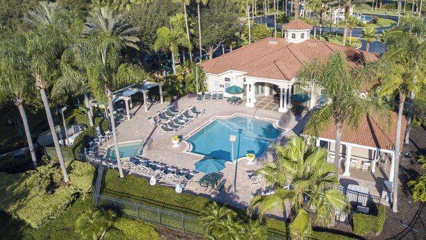 An aerial view of a resort with a swimming pool, lounge chairs, and palm trees. - Asteria – Your perfect stay close to Theme Parks. (Kissimmee)