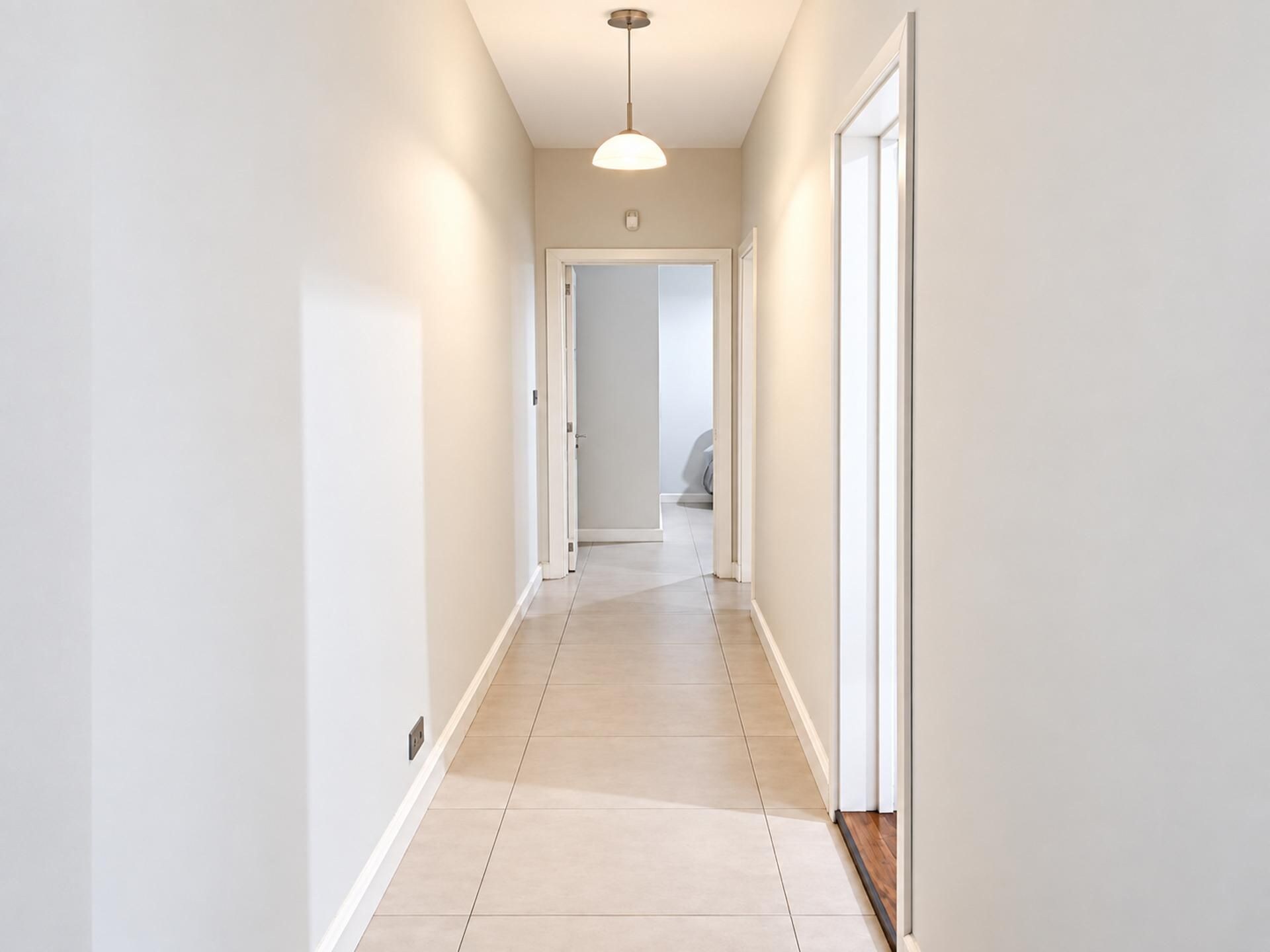 A narrow, light-colored hallway with a ceiling light fixture and a door at the end.