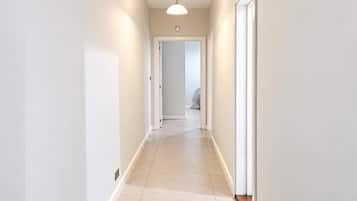 A narrow, light-colored hallway with a ceiling light fixture and a door at the end.