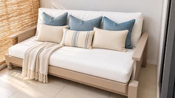 A bed with a beige frame, white bedding, and multiple pillows in shades of blue and beige.