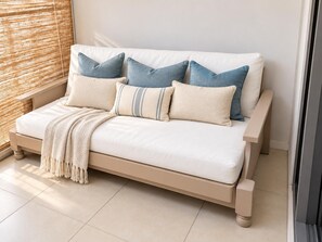 Un lit avec un cadre de couleur beige, une literie blanche et plusieurs oreillers dans différentes nuances de bleu et de beige.