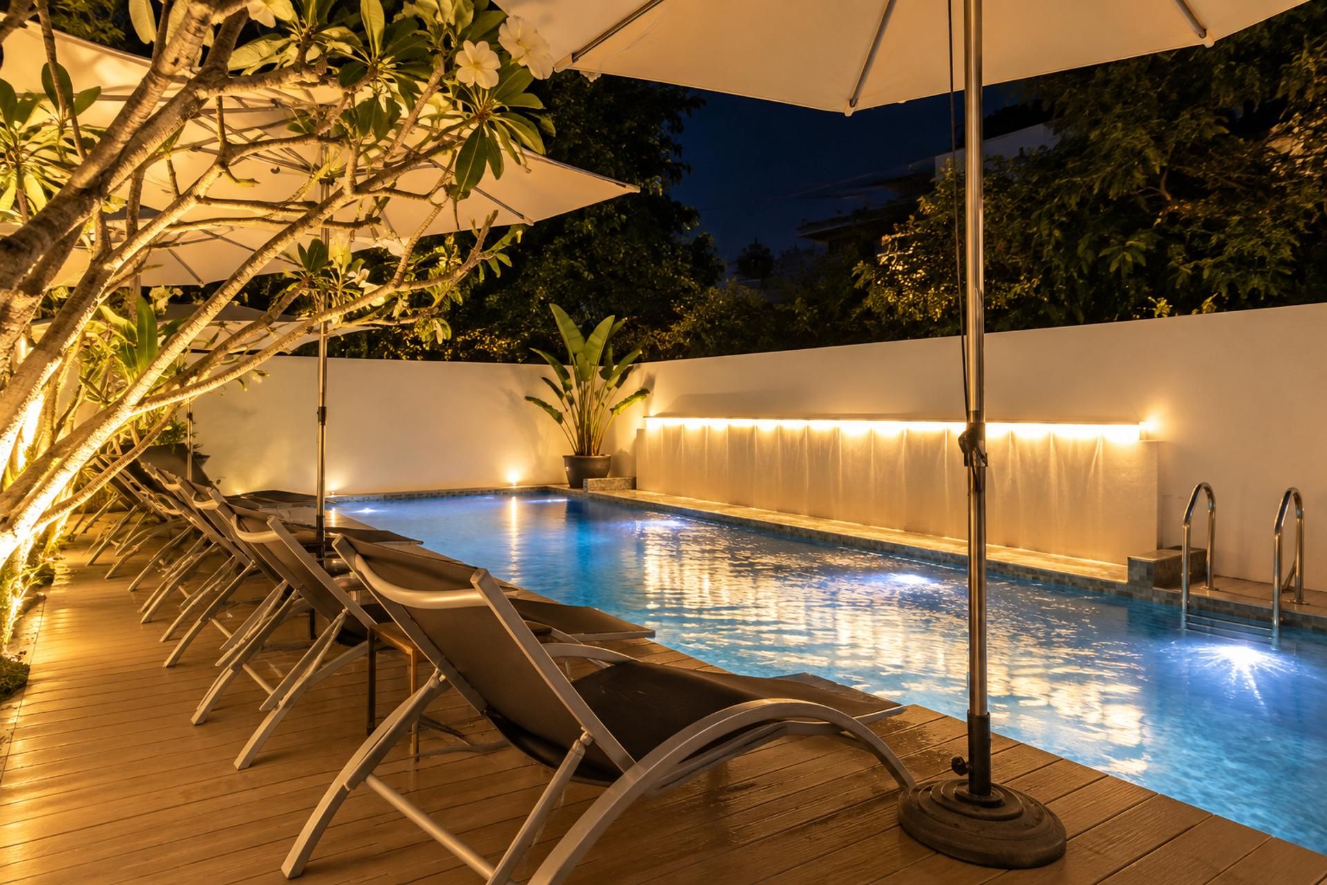 An outdoor swimming pool with lounge chairs and a waterfall feature.