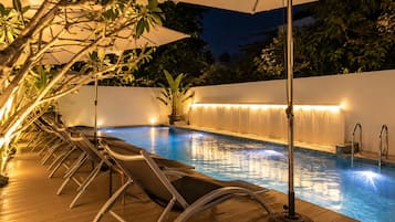 An outdoor swimming pool with lounge chairs and a waterfall feature.