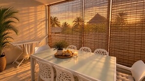 A sunlit patio with a table, chairs, a potted plant, and a candle. - Spacious 2-bed Near Beach With Pool (Grand-Baie)