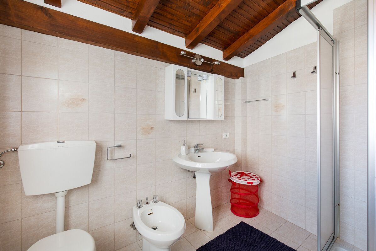 A bathroom with a toilet, bidet, sink, and shower.