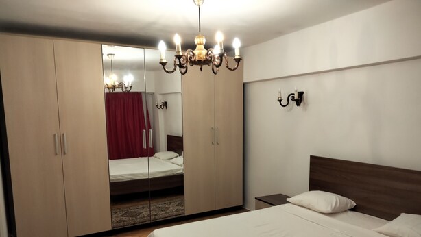 A bedroom with a large wardrobe, a bed, a nightstand, and a chandelier. - Libertatii 22, old City, central (București)