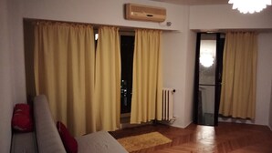 A room with a sofa, yellow curtains, a radiator, and a wooden floor. - Libertatii 22, old City, central (București)