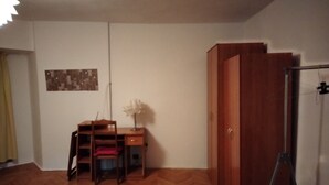 A room with a wooden herringbone floor, a desk with a chair, a cabinet, and a refrigerator. - Libertatii 22, old City, central (București)