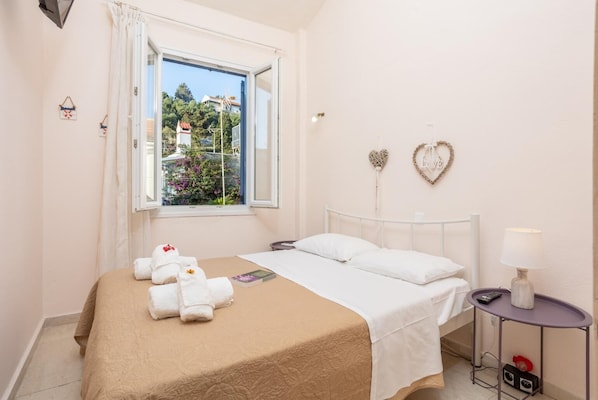 Une chambre à coucher comprenant un lit, une fenêtre, une table de chevet avec une lampe et des éléments décoratifs en forme de cœur accrochés au mur.
