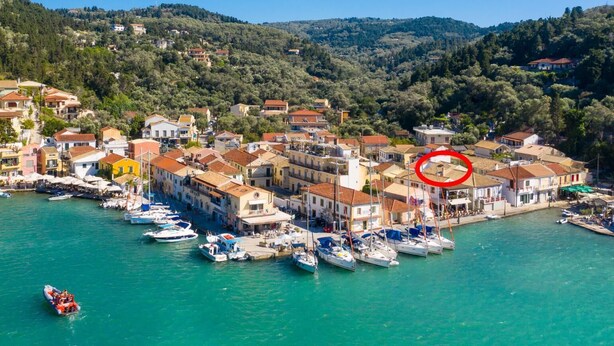 A coastal town with a marina, houses with red-tiled roofs, and a hilly backdrop.