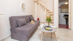 A modern living room with a grey sofa, a round coffee table, and a small side table with a vase of flowers.
