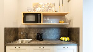 A kitchen with a microwave, coffee maker, and a bowl of lemons on the counter.