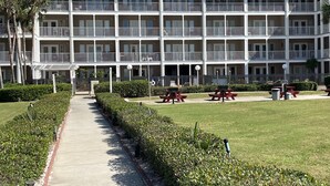 Un hôtel à plusieurs étages doté d’une cour intérieure, d’un espace extérieur aménagé pour s’asseoir et d’une pelouse bien entretenue.