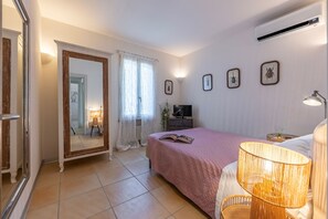 A bedroom with a bed, a TV, a lamp, and a mirror.