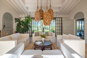A spacious living room with white sofas, a round coffee table, and a large window providing a view of the outdoors. - Villa Le Cave 12, Emma Villas (Campalto)