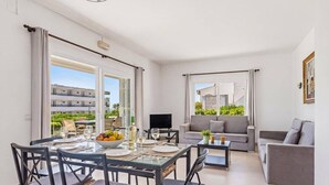 Un salon moderne avec un coin repas, un canapé gris et un téléviseur.