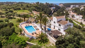 A white villa with a swimming pool, surrounded by lush greenery and a clear view of the sea. - Villa Mas Alta by Villa Plus (Ferreries)