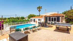A pool area with a sunbed, a table, and a ping pong table.