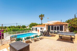 A pool area with a sunbed, a table, and a ping pong table.