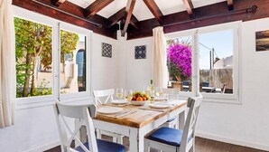 A dining area with a wooden table, white chairs, and a view of the outdoors.