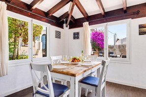A dining area with a wooden table, white chairs, and a view of the outdoors.