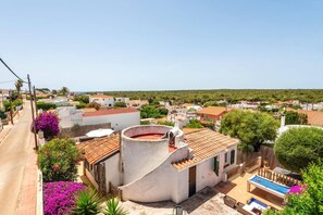 Un quartier résidentiel doté d’une piscine, d’un bâtiment blanc surmonté d’un toit en tuiles rouges et entouré de verdure.